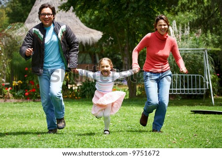 happy family smiling and running outdoors towards the camera