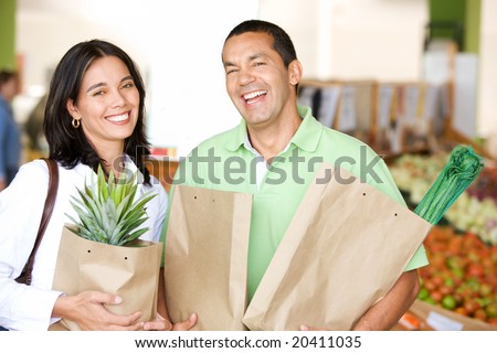 Beautiful couple smiling at a supermarket carrying shopping bags