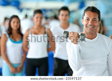 man lifting free weights at the gym with a group of people behind him
