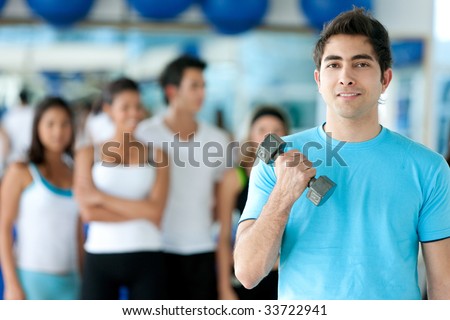 man at the gym exercising with free weights in front of a group