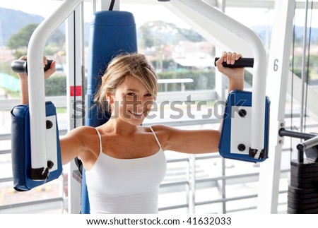 Woman at the gym doing arms exercises on a machine