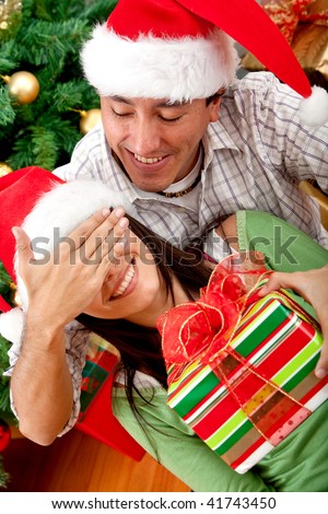 Man giving a surprise Christmas gift to a woman