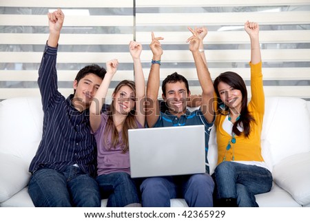 Excited group of people sitting on the sofa with a laptop