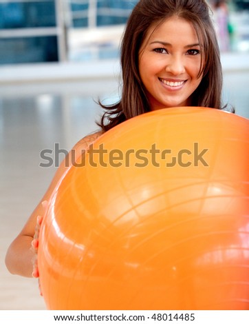 beautiful woman leaning on a pilates ball at the gym