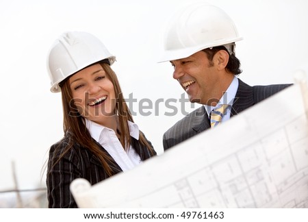 Architects at a construction site wearing helmets and smiling