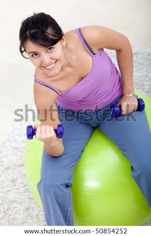 Woman exercising at home with weights and a pilates ball