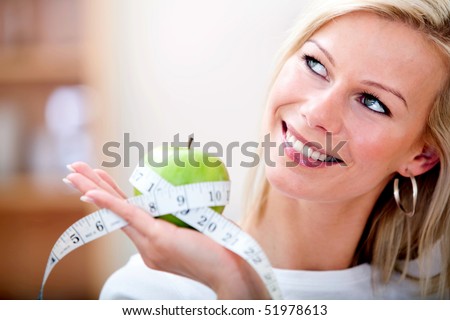 Healthy eating woman holding an apple with a measuring tape around it