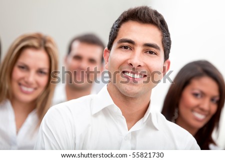 Business man smiling with a group behind at the office
