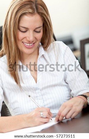 Business woman signing some documents at the office and smiling