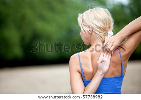 Fit woman doing stretching exercises outdoors for her back