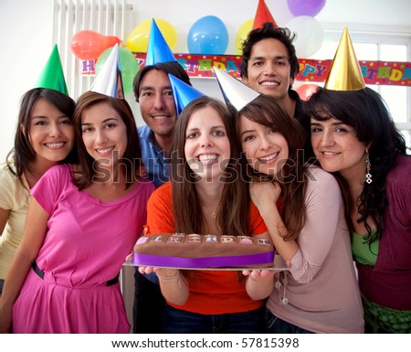 Group of people at a birthday party having fun and holding the cake