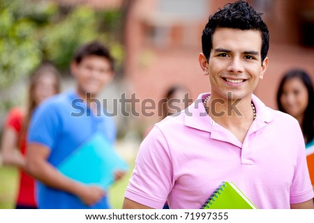 Male student carrying notebooks outdoors and smiling