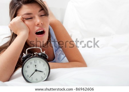 Sleepless woman lying in bed looking at the hours pass by