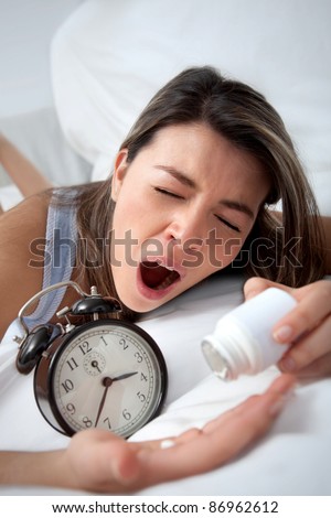 Desperate sleepless woman taking sleeping pills and yawning