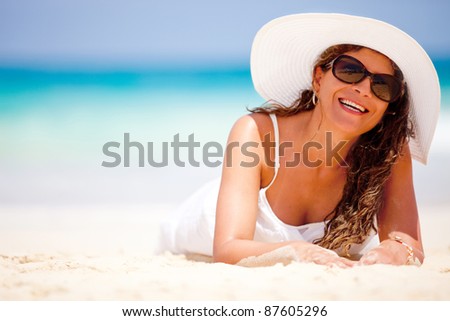 Woman lying on sand at the beach and smiling
