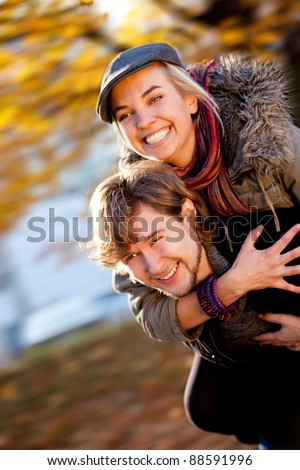Playful couple with a man giving a piggyback ride to his girlfriend outdoors