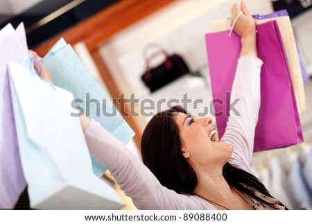 Very happy shopping woman with arms up holding bags