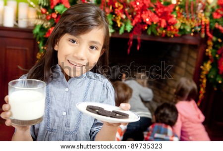 Girl holding milk and cookies for Santa Claus at Christmas day