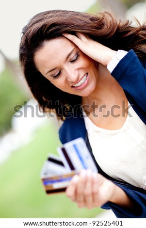 Stressed shopping woman in a financial dilemma holding three credit cards