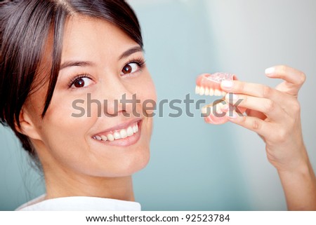 Woman holding a teeth sample or prosthesis at the dentist