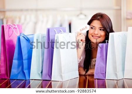 Beautiful woman with shopping bags holding a sale tag