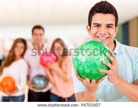 Happy man holding a bowling ball playing with friends