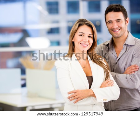 Happy business couple with arms crossed at the office