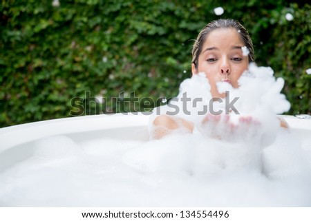 Happy woman taking a bubble bath and being playing with foam