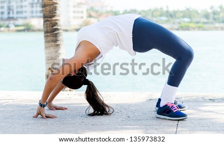 Beautiful fit woman stretching her back outdoors