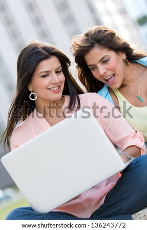 Female friends social networking on a laptop computer