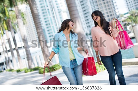 Female shoppers having fun and laughing while carrying baga