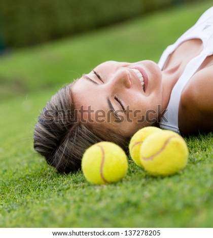 Thoughtful female tennis player lying on lawn