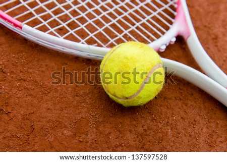 Tennis racket with ball on a clay court