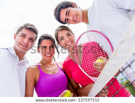 Happy group of tennis players holding rackets outdoors