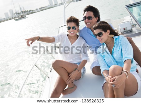 Happy group of friends sailing on a boat and pointing away