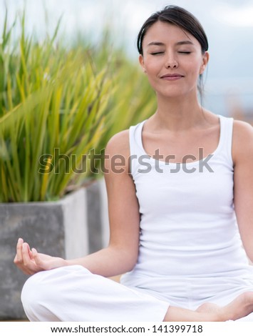 Woman doing yoga and meditating with eyes closed