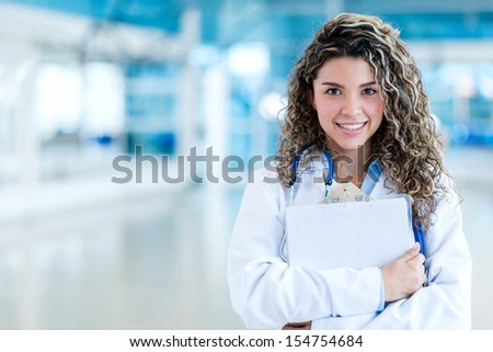 Happy female doctor holding clipboard at the hospital