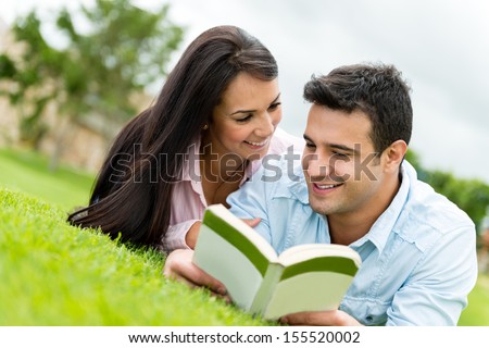 Beautiful couple on a romantic date outdoors reading a book