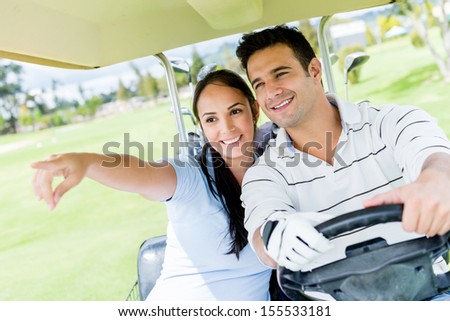Happy couple at the golf course driving a cart