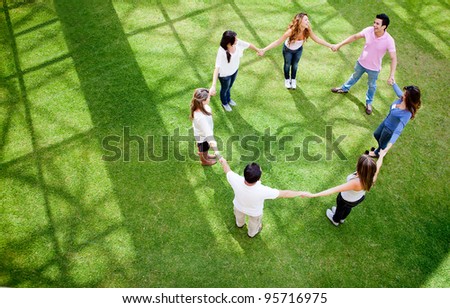 Group of friends holding hands in a circle - outdoors