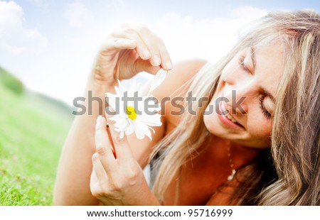 Woman with a daisy flower playing he loves me or not