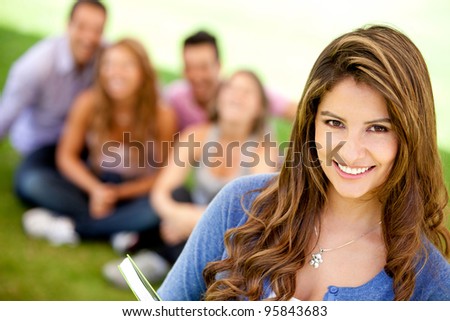 Female student smiling outdoors with a group of friends