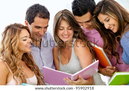 Happy group of young students with a notebook outdoors
