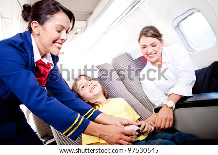 Flight attendant fastening seat belt to boy for a safe trip