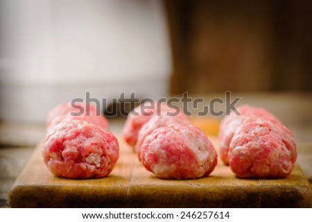Raw meat balls on a chopping board. Selective focus. On a background the meat grinder.