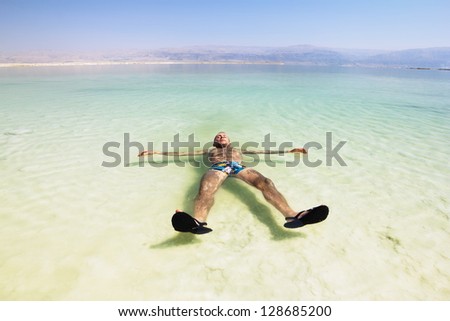 A man rests his hand on the water of the dead sea in Israel