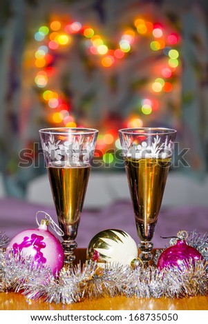 Goblets with sparkling wine and festive toys amid colorful heart-shaped Bokeh