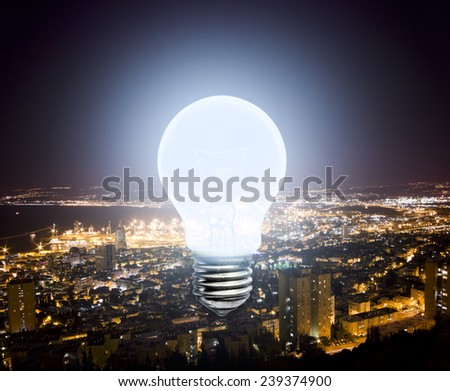 The burning light bulb on the background lights of the night city