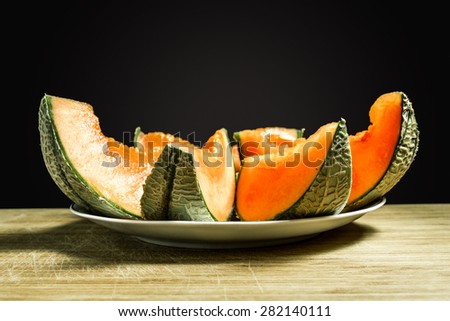 Slices of succulent Orange melon lie on a plate