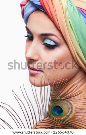 Portrait of young beautiful woman in a turban and peacock feather in oriental style